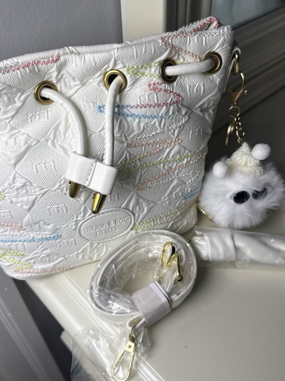 White Quilted Mini Bucket Bag with Pastel Stitching and Pom Charm